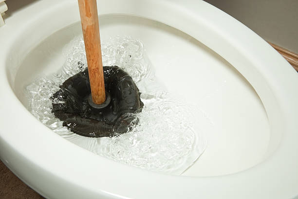 Plunger working on Toilet Clog A rubber plunger is working on a toilet clog and displacing water. clogged stock pictures, royalty-free photos & images