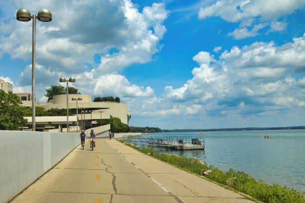 Lake Monona in Madison Sunny Summer day landscape of Lake Monona and Monona Terrace with bikers riding on a lakeshore trail in Madison, WI. lake monona photos stock pictures, royalty-free photos & images