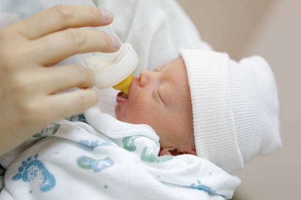 madre botella de alimentar a su bebé prematuro en el hospital nursery - premature fotografías e imágenes de stock