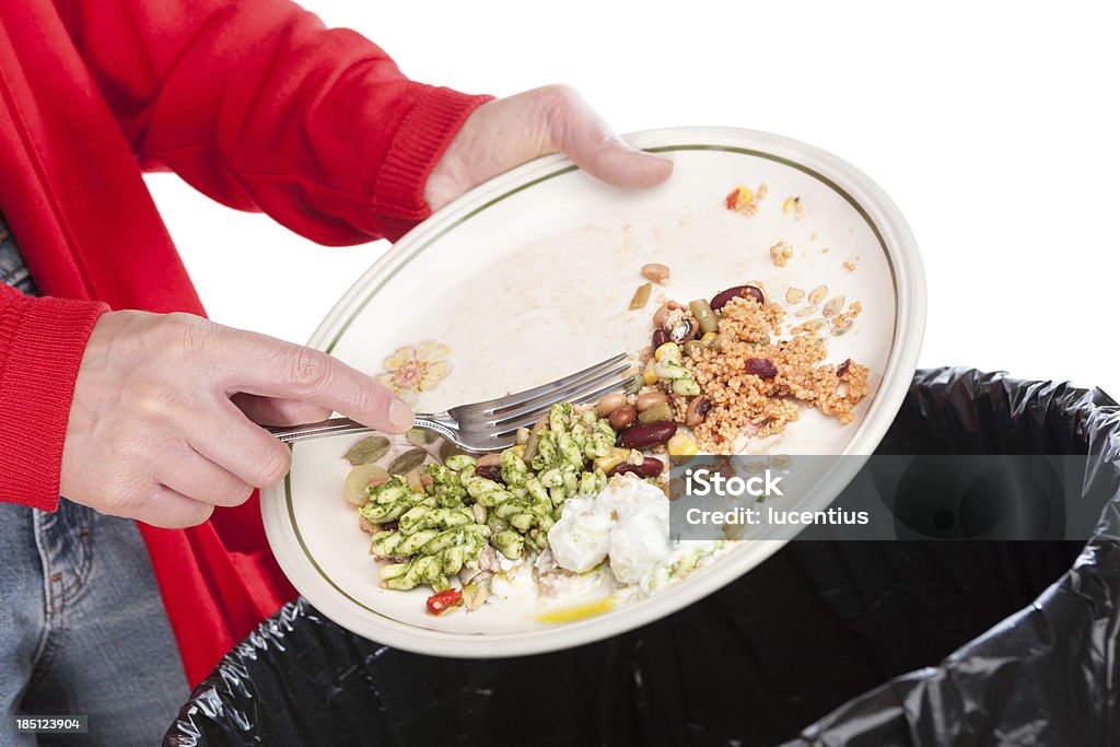 Emptying food leftovers into rubbish bin Close-up of a woman sweeping the leftovers from a meal into a domestic garbage bin. The background is pure white. Food Stock Photo