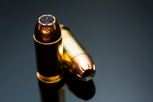 Two.45 caliber hollowpoint bullet on a reflective grey background.All images in this series...