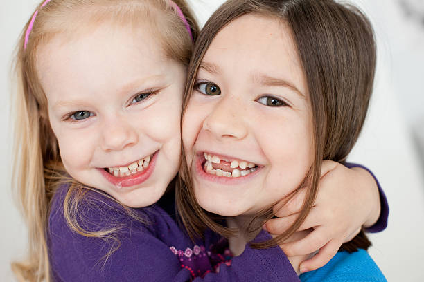 クローズアップカラーの 2 つの幸せな姉妹沿う - embracing smiling gap children only ストックフォトと画像