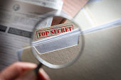 Someone looking at top secret files with magnifying glass
