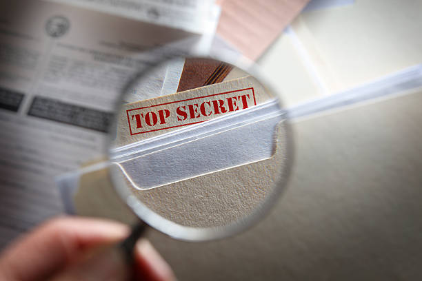 Someone looking at top secret files with magnifying glass stock photo