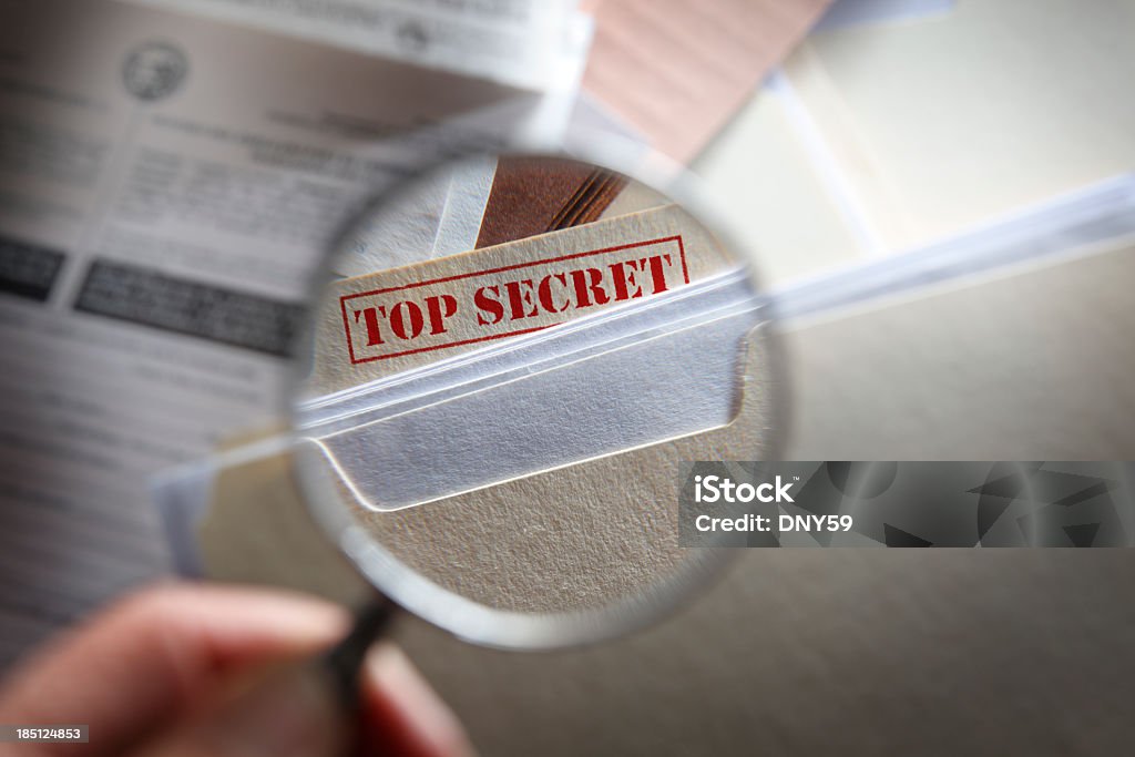Человек смотреть в top secret файлов с увеличительным стеклом - Стоковые фото Приватность роялти-фри
