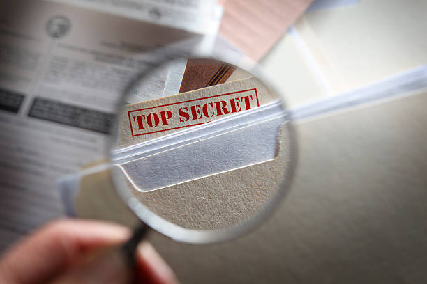 человек смотреть в top secret файлов с увеличительным стеклом - top secret secrecy mystery data стоковые фото и изображения