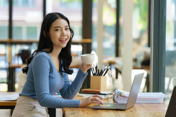 istock Beautiful young asian business woman drinking coffee and using laptop computer while working in office. 1851249965
