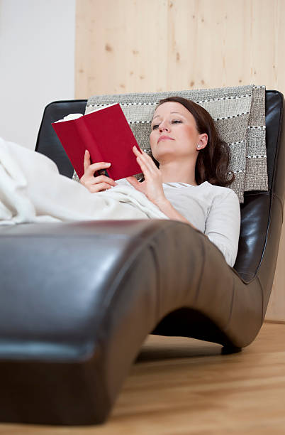 istock Young woman is relaxing and reading on a couch 185125647