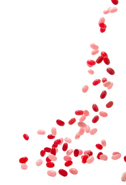 Photo of falling red and pink jelly beans on white background