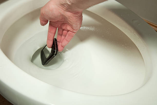 トイレの手になるには、携帯電話番号を取得する - mobile phone smart phone toilet water ストックフォトと画像