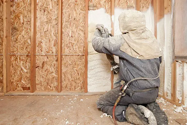 Photo of Worker Spraying Expandable Foam Insulation between Wall Studs