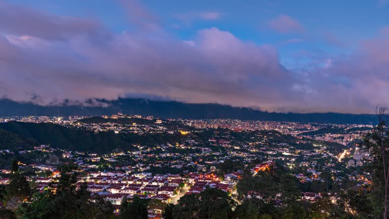 day to night time lapse aerial view of Caracas city valley with El Avila Mountain at the background