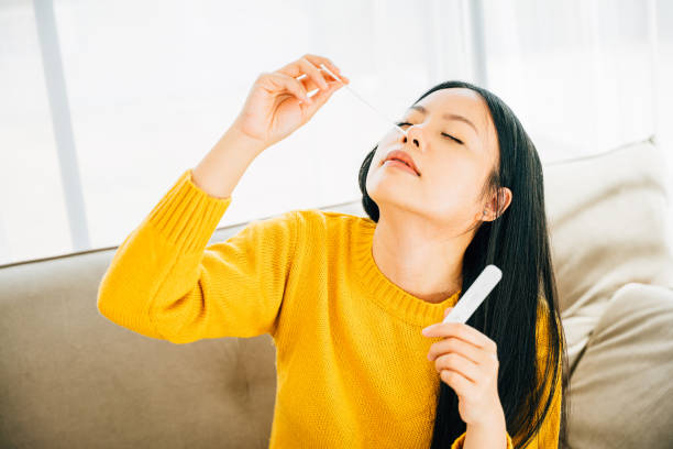 istock Woman at home uses a rapid antigen test kit inserting a swab into her nose 1851267590