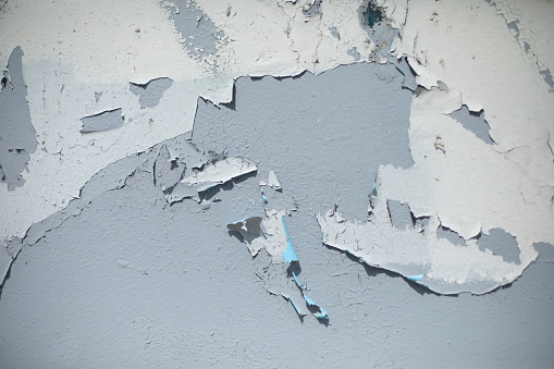 Old paint on gray wall. Flying paint. Ruined background. Old traces.