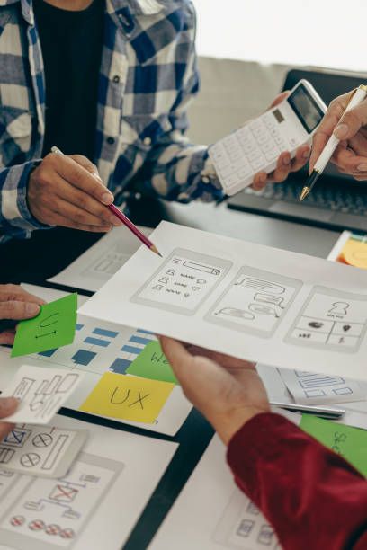 istock UX developers or company employees design user interfaces or UI prototypes for mobile applications or website software that display the software on smartphone screens. Vertical close-up image 1851307359