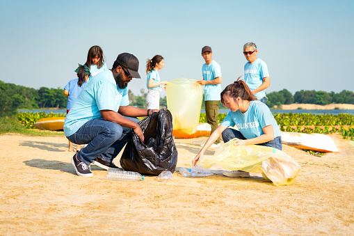 group of diverse people,environmental conservation activist keeping plastics waste by the river,volunteers,plastic waste,environmental conservation