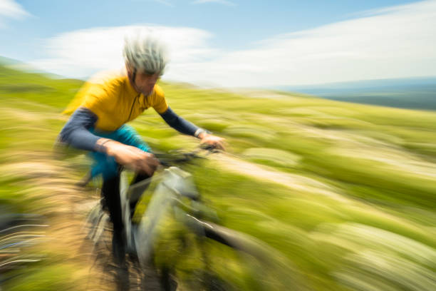 Man riding electric bike fast on mountain road, blurred motion view
