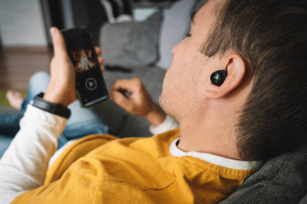 beautiful man is watching a movie on her smartphone. Viewing video clips on Internet by guy. listen music with phone. young beautiful man is watching a movie on her smartphone. Viewing video clips on Internet by guy. listen music with phone. movie sound clips stock pictures, royalty-free photos & images