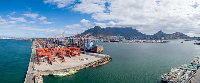 Aerial view panoramic oil tanker moving pass sea port warehouse and container ship or crane ship working for delivery containers shipment. Suitable use for energy power or transport or import export to global logistics concept.