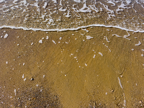 Sea waves coming to an empty beach on a sunny day. No people.