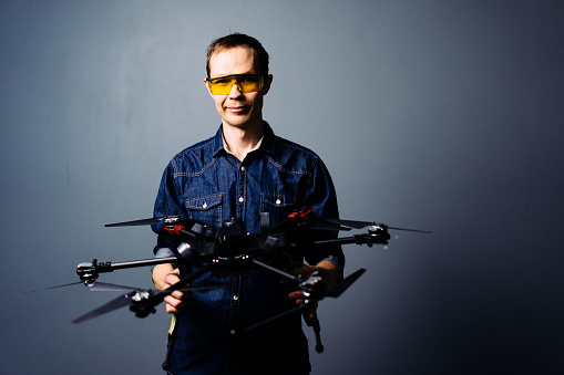 Engineer holding fpv racing drone on blue background. Starting motors