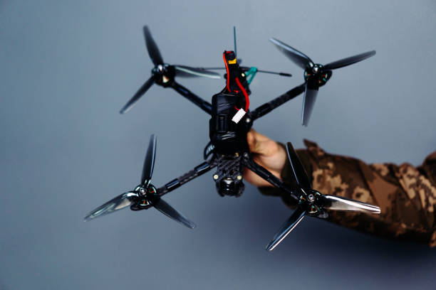 istock Hand holding fpv racing drone on blue background. Starting motors 1851445317