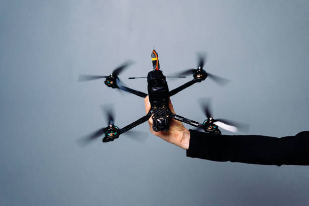 istock Hand holding fpv racing drone on blue background. Starting motors 1851445826