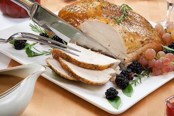 Roasted Turkey Breast - Rosemary-Basil Rub Carving Rosemary-basil rub roasted turkey breast garnished with grapes, blackberries, and fresh basil, and rosemary in fall themed surrounding. roast turkey stock pictures, royalty-free photos & images
