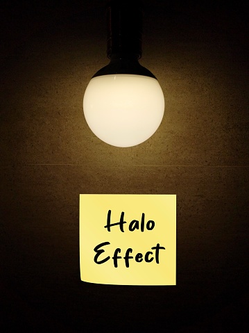 Light bulb with text stick note written Halo Effect -  cognitive bias in which overall impression of person, influences how we feel and think about their character
