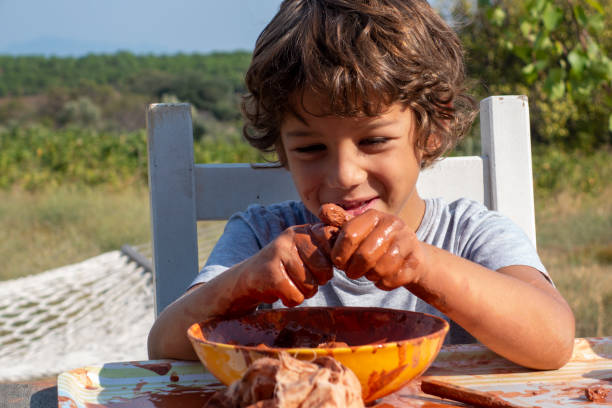 istock Boy playing with ceramic clay. He works for his creativity. A 9-year-old boy playing with ceramic clay in a bowl. He works at the table on the porch of the house. 1851455689