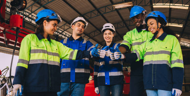istock A diverse group of engineers and workers wearing life jackets and helmets join hands together as a working team in an industrial plant and machining. 1851471182