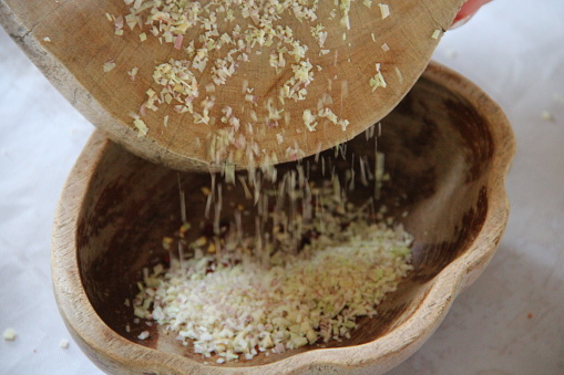 A wooden bowl with a sieve filled with a small quantity of cereal grains.