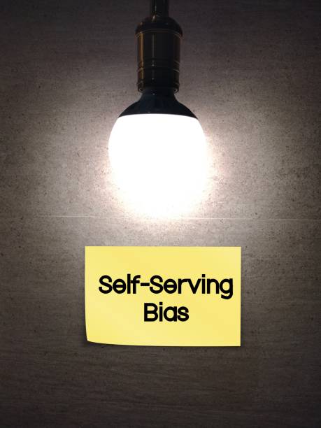 istock Lamp light bulb on dark wall with stick note Self-Serving Bias - refers to a tendency cognitive bias to attribute positive events to self, but attribute negative results to others - serve as defense mechanism 1851548034