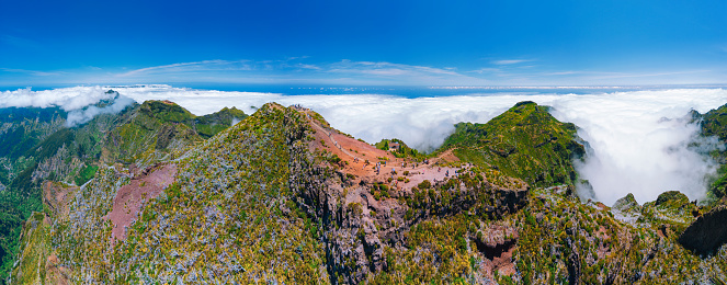 Panoramic image of a mountain slope in the San Gabriel Mountains range in Southern California. This images includes a blue sky and broken clouds, snow, and pine trees.