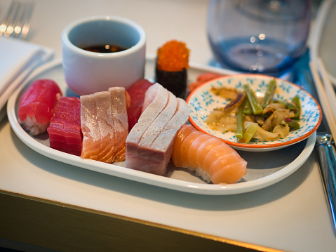 A mixed plate of fresh sashimi with tuna, salmon, kingfish, combination of sushi served with a side plate of salad and sashimi soy sauce.