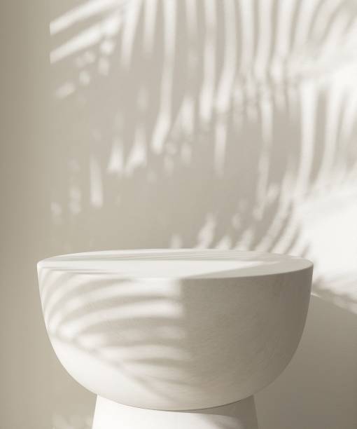 istock Cream white round podium table in sunlight, palm tree leaf shadow on wall 1851569493
