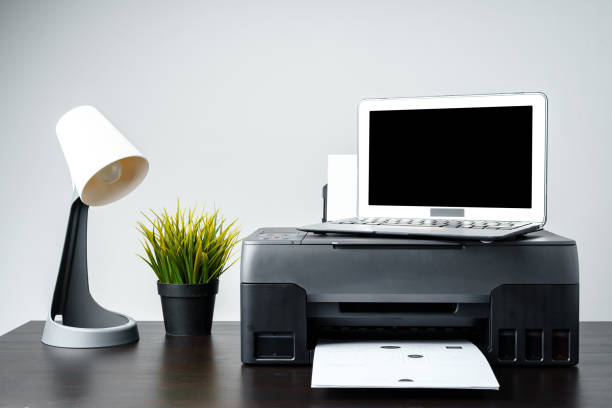 istock Modern printer with paper and laptop on table in office 1851608447