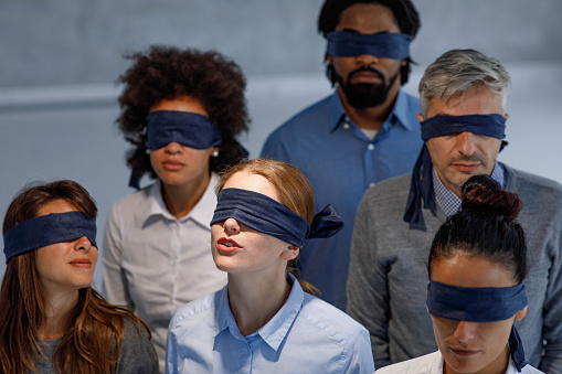 Group of blindfolded business people in the dark in the office.