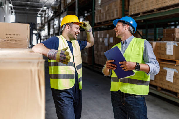 istock Happy inspector and manual worker talking in a warehouse. 1851621036
