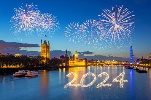 London's Westminster Palace and London Eye with the year 2024 sparkler inscription and fireworks
