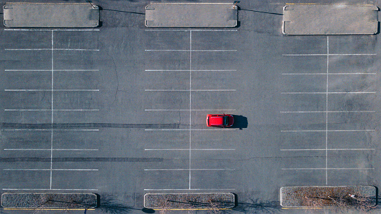 A red car is standing alone in the parking lot. View from a drone