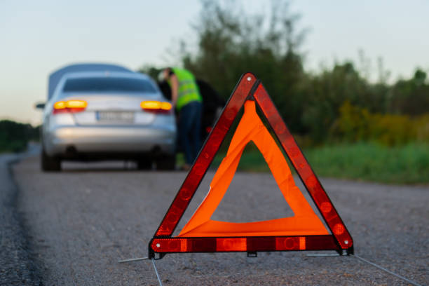 istock Unrecognizable sad driver in reflective vest. Male driver standing near broken car with open up hood. Red triangle to warn other road users of car breakdown or engine failure stop at countryside highway. Emergency traffic 1851682005