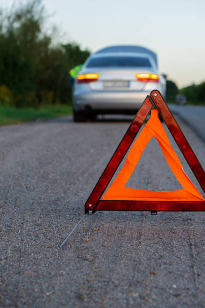 istock Unrecognizable sad driver in reflective vest. Male driver standing near broken car with open up hood. Red triangle to warn other road users of car breakdown or engine failure stop at countryside highway. Emergency traffic 1851684783