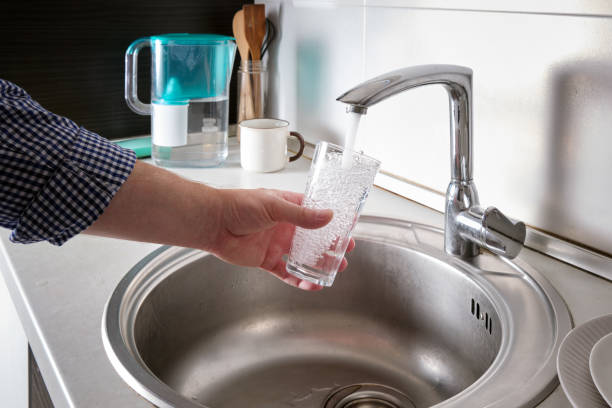 istock A man draws water from the tap into a glass cup in his home kitchen. 1851704552