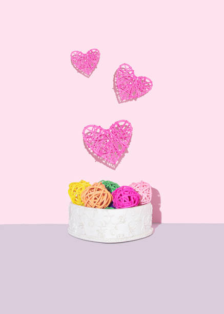 Pink hearts levitate on pastel pink background. Front view.