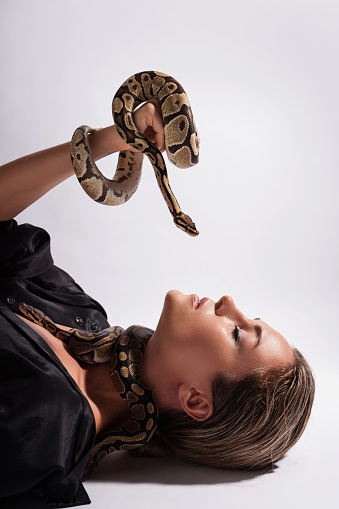 Beautiful woman with python snakes elegantly slithering over her body.