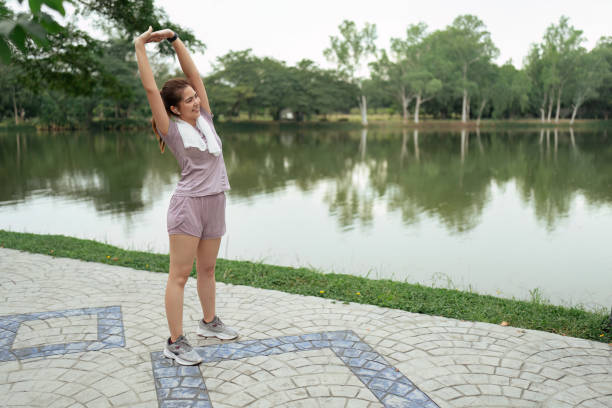 mulher com roupas esportivas se alonga antes de correr pela manhã - aquecimento físico - fotografias e filmes do acervo