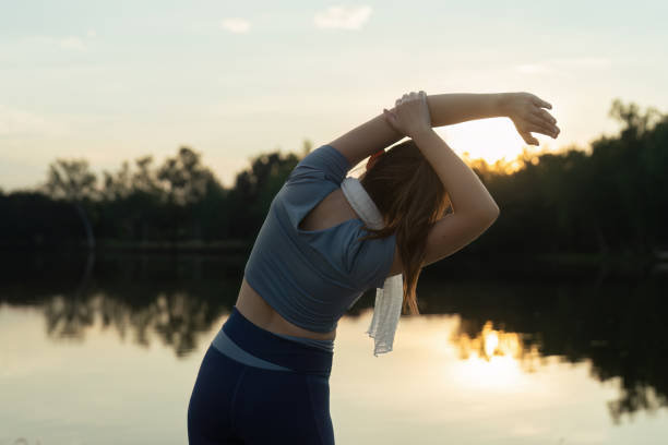 mulher com roupas esportivas se alonga antes de correr pela manhã - aquecimento físico - fotografias e filmes do acervo