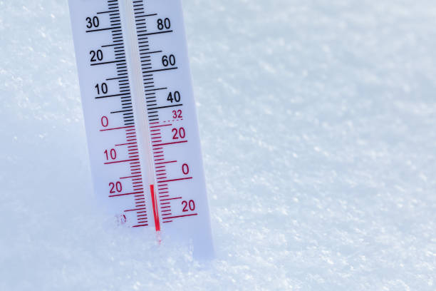 Thermometer with both Celsius and Fahrenheit scales placed in fresh snow indicating freezing cold winter temperature