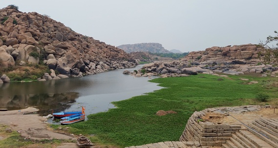 Serene landscape in Hampi, India: A tranquil lagoon nestled amidst majestic mountains.The scene captures the tranquility of Hampi, with calm waters reflecting the breathtaking mountainous surroundings.